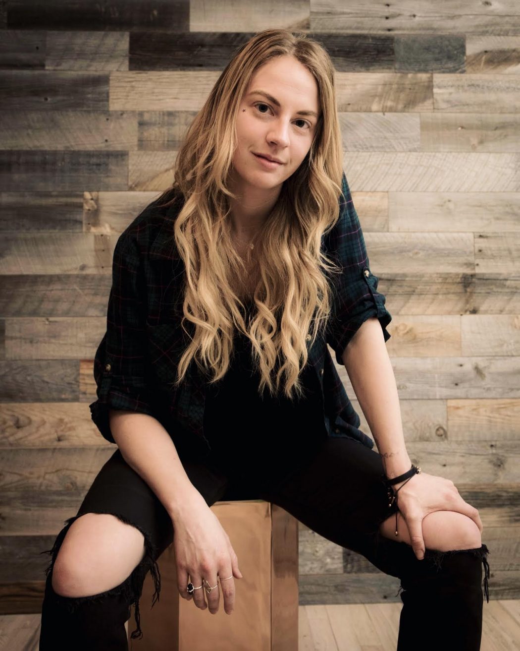 Heyley wearing black sits on a block of wood