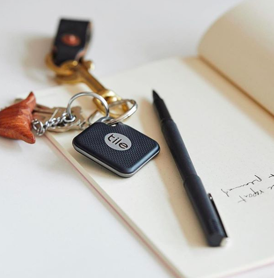 Tile bluetooth tracker on keys sitting on a notebook