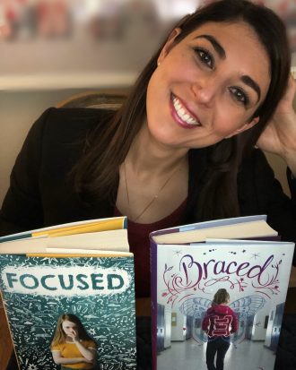 Alyson smiles with her two books, "Focused" and "Braced"