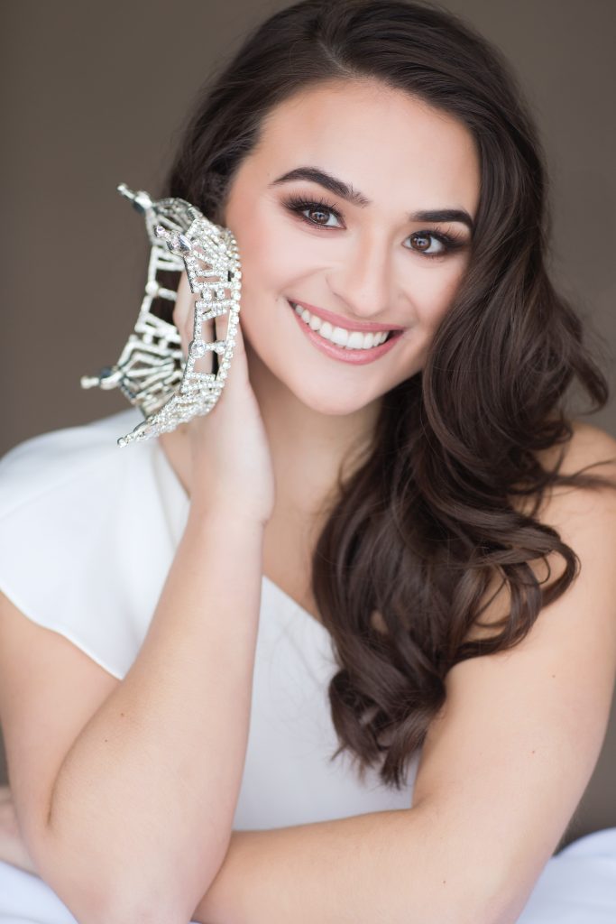 Amanda's headshot smiling and holding the Miss Great Lakes crown in her right hand.