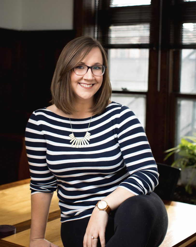 Dani smiles wearing a striped black and white top and cool chunky necklace.