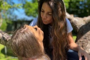 Dr Luiza Sanz and her daughter blow each other air kisses in front of a beautiful green tree