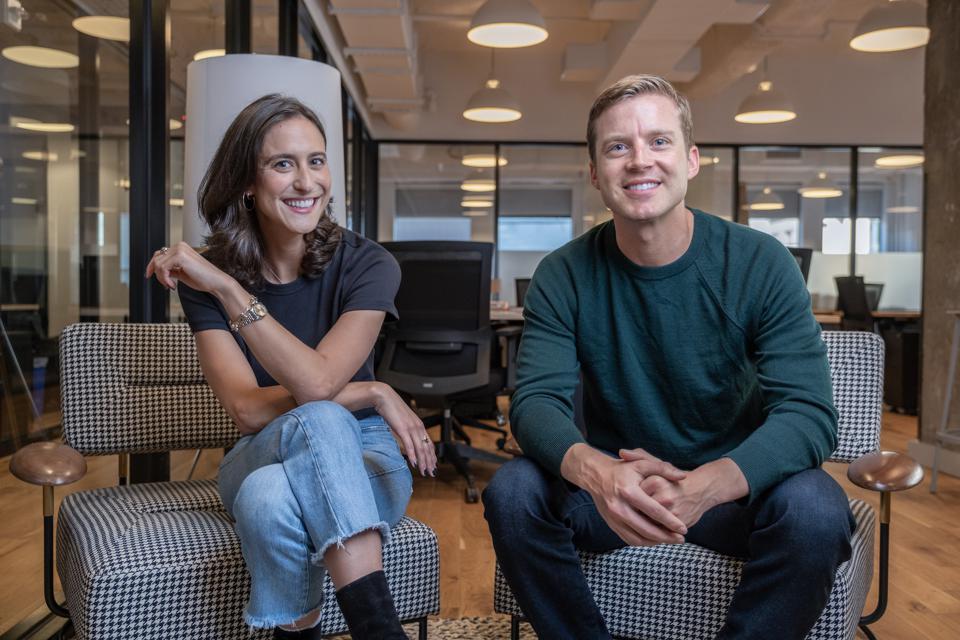 Emily Yudofsky and Stefan Bauer, co-founders of Marker Learning sitting next to each other in the office, smiling.